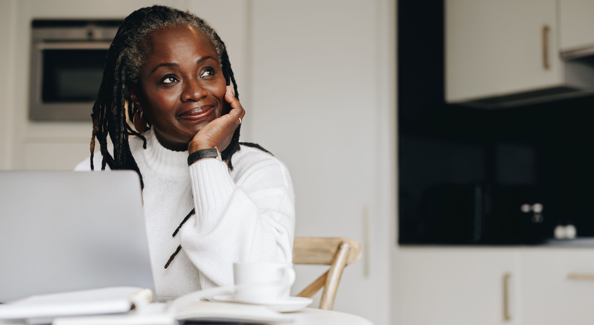 Mature businesswoman looking away thoughtfully in her home office